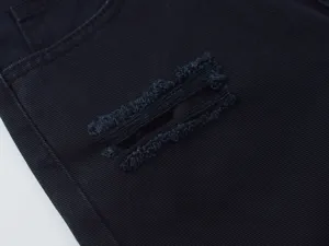 Close-up detail of black denim jeans showcasing stylish distressed frayed slit and texture.