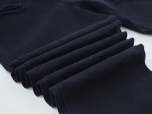 Close-up detail shot of dark denim fabric texture, folded neatly to show quality.