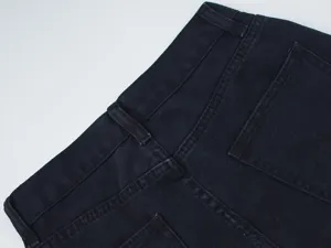 High quality dark denim jeans back pocket and waistband detail close up showing fine stitching.