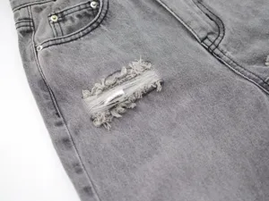 Grey distressed straight denim jeans detail shot showcasing ripped fabric and pockets.