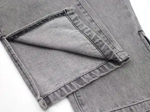 Close-up detail of women's gray straight-leg denim pants featuring a stylish hem slit design.