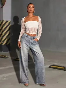 Detailed view of white lace long sleeve top and rhinestone embellished wide leg jeans.
