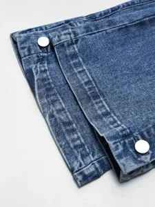 Close-up of split hem straight jeans with metal snap buttons, stylish denim detail view