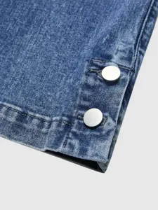 Close-up detail of women's denim jeans cuff with stylish metal snap button decorations.