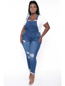Close up of plus size ripped stretch denim overalls with front pocket and adjustable straps.