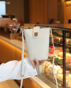 Detail view of genuine leather women bucket shoulder bag with elegant metal lock and strap.