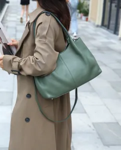 Close-up detail of the stylish green leather shoulder bag worn with a trench coat in street style.