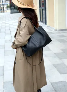 Detailed view of the black leather shoulder bag worn outdoors, showcasing texture and style.