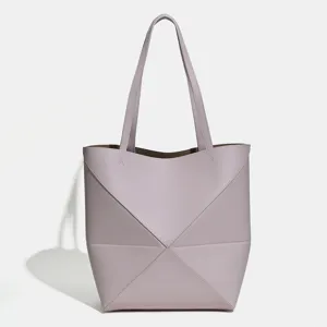 Nahaufnahme des geometrischen Faltdesigns und Riemens der lila Schultertasche.