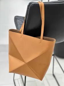 Detailansicht der stilvollen braunen geometrischen Ledertasche an einem modernen Stuhl.