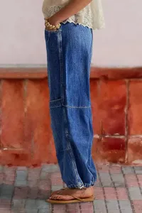 Side view detail of loose denim pants featuring cinched cuffs and curved leg design.