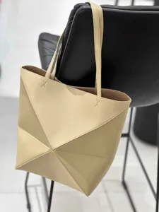 Detailaufnahme einer minimalistischen beigen geometrischen Origami-Tasche am modernen Stuhl.