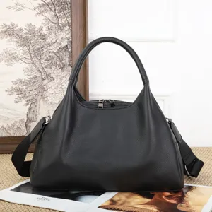 Dettaglio borsa in pelle nera, grande borsa a nuvola con doppia zip e tracolla regolabile.