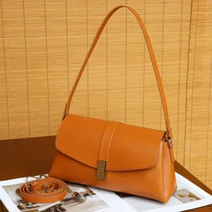 Detail view of stylish orange vegan leather underarm shoulder bag with metal H clasp.
