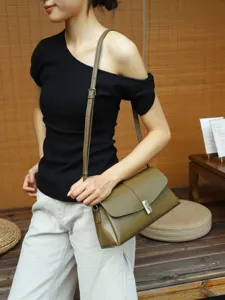 Olive green leather envelope shoulder bag, detail view showing metal clasp and strap.