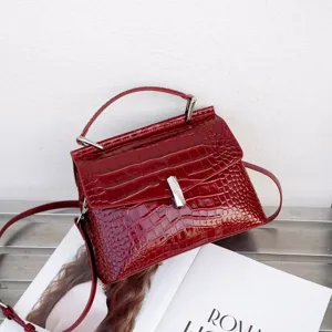 Red crocodile texture handbag detail, elegant top handle and metal clasp design for women.
