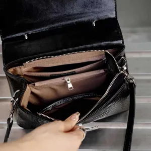Detailed view of the black crocodile pattern handbag interior compartments and sturdy metal zippers.