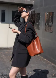 Detail view of brown leather bucket bag, minimalist commuter style, large capacity shoulder strap.