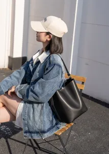 Detail view of stylish black leather bucket bag, perfect for autumn winter daily commute.