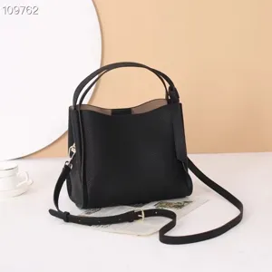 Detailed view of black leather shoulder bag with double handles and metal hardware.