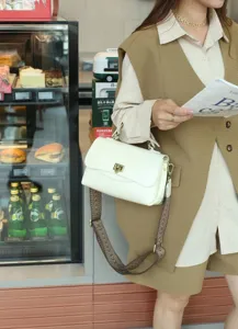 Gedetailleerd overzicht van de elegante witte lederen tas met vintage band en slot.