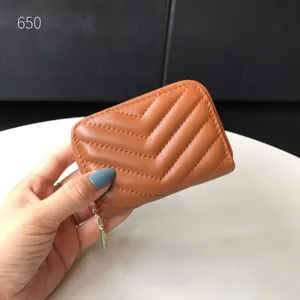 Primo piano dettagliato del porta carte trapuntato in pelle marrone con zip e cuciture.