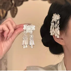 Close-up detail shot of ethnic Miao silver tassel hair clip showing exquisite filigree design.