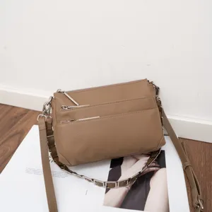Detail shot of brown genuine leather multi-zipper crossbody bag with chain strap.