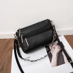 Detailed view of black genuine leather multi-zipper crossbody bag with metal chain strap.