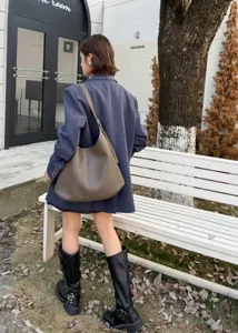 Detailed view of women's leather shoulder bag worn outdoors, showing daily style and capacity.