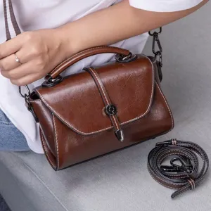 Close-up detail of retro brown oil wax leather shoulder bag with chic metal lock closure.