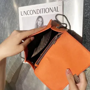 Orange leather crossbody bag with metal chain strap, structured flap design for daily fashion wear.