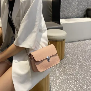Detail of pink litchi leather women crossbody bag with metal lock and chain strap for chic daily wear.