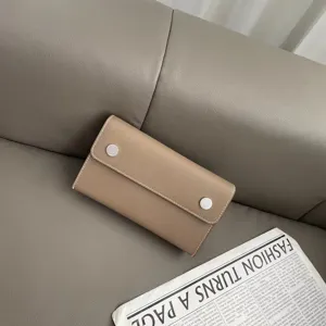 Detailaufnahme der minimalistischen Echtleder Umhängetasche, elegantes Taupe mit Druckknöpfen.