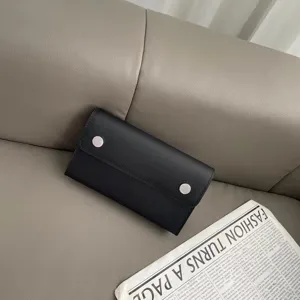 Detaillierte Nahaufnahme einer schwarzen Leder-Smartphone-Tasche mit Metallknöpfen.