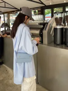 Hellblaue Leder Umhängetasche Detail im modernen Café, stilvolles Alltagsoutfit für Damen.
