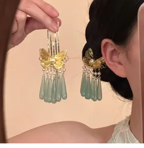 Close-up detail shot of Chinese traditional gold butterfly hairpin with green tassel drops.