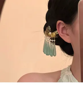 Close-up detail of neo-chinese gold butterfly hair comb with elegant green tassels.