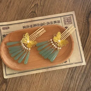 Detailed view of traditional Chinese Hanfu hair combs with gold butterfly and green tassels.