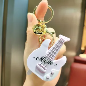 Detailed close-up view of a cute mini music guitar keychain with golden metal ring and functional buttons.
