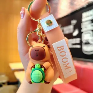 Close-up detail shot of cute cartoon capybara holding turtle keychain with silicone strap.
