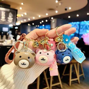 Detail view of cute cartoon bear head keychains with bells and straps in multiple colors.