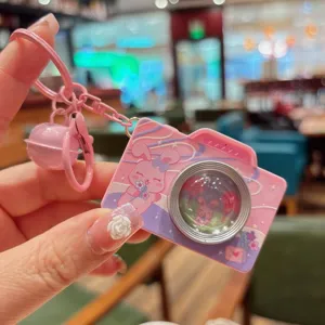 Leuke roze cartoon camera sleutelhanger met vloeibare glitters en een leuk belletje