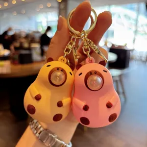 Close up view of cute cartoon capybara squeeze bubble keychain pendant in yellow and pink colors.