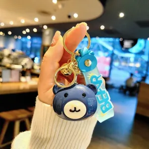 Cute blue bear keychain detail view, acrylic doll pendant with gold metal ring and strap.