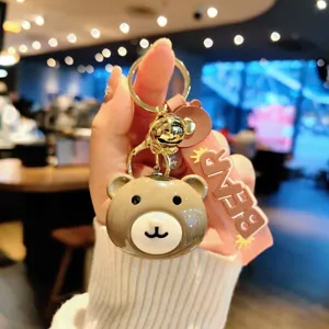 Cute brown bear keychain detail with metal ring, bell and pink strap for bags.