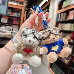Vue détaillée de porte-clés en peluche ours mignon avec lunettes de soleil et pull.