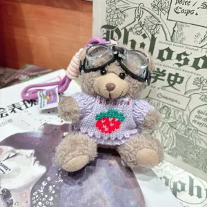 Gros plan détaillé d'un joli porte-clés ours en peluche avec lunettes et pull fraise.