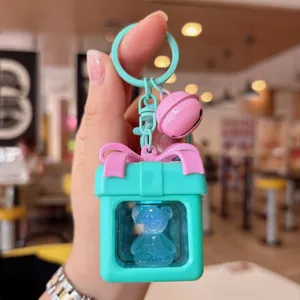 Detalle en primer plano del llavero de oso luminoso en una caja de regalo con lazo rosa.