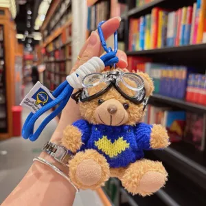 Gros plan d'un porte-clés en peluche ours mignon avec lunettes de aviateur et pull.